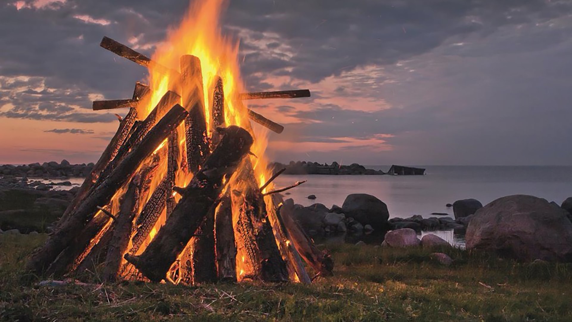 Bild eines Lagerfeuers in der Dämmerung am Meer